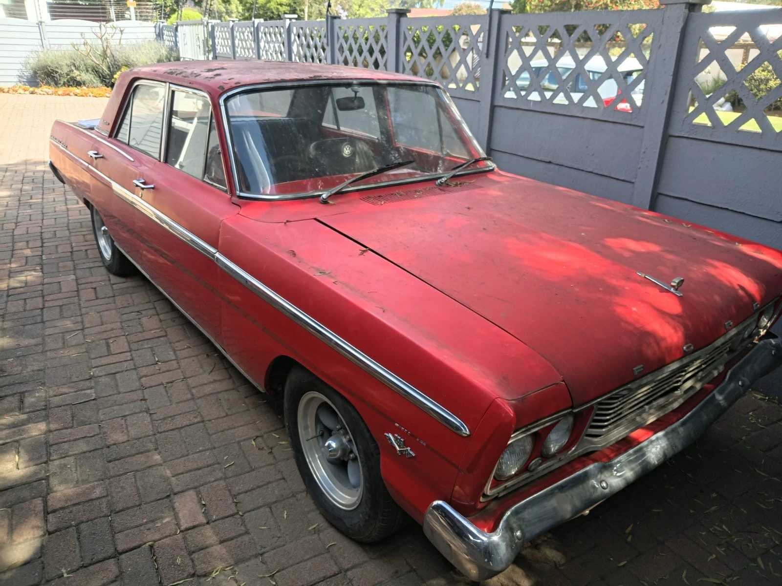 The red Fairlane before restoration, showing the four-door body, side brightwork and existing wheels.